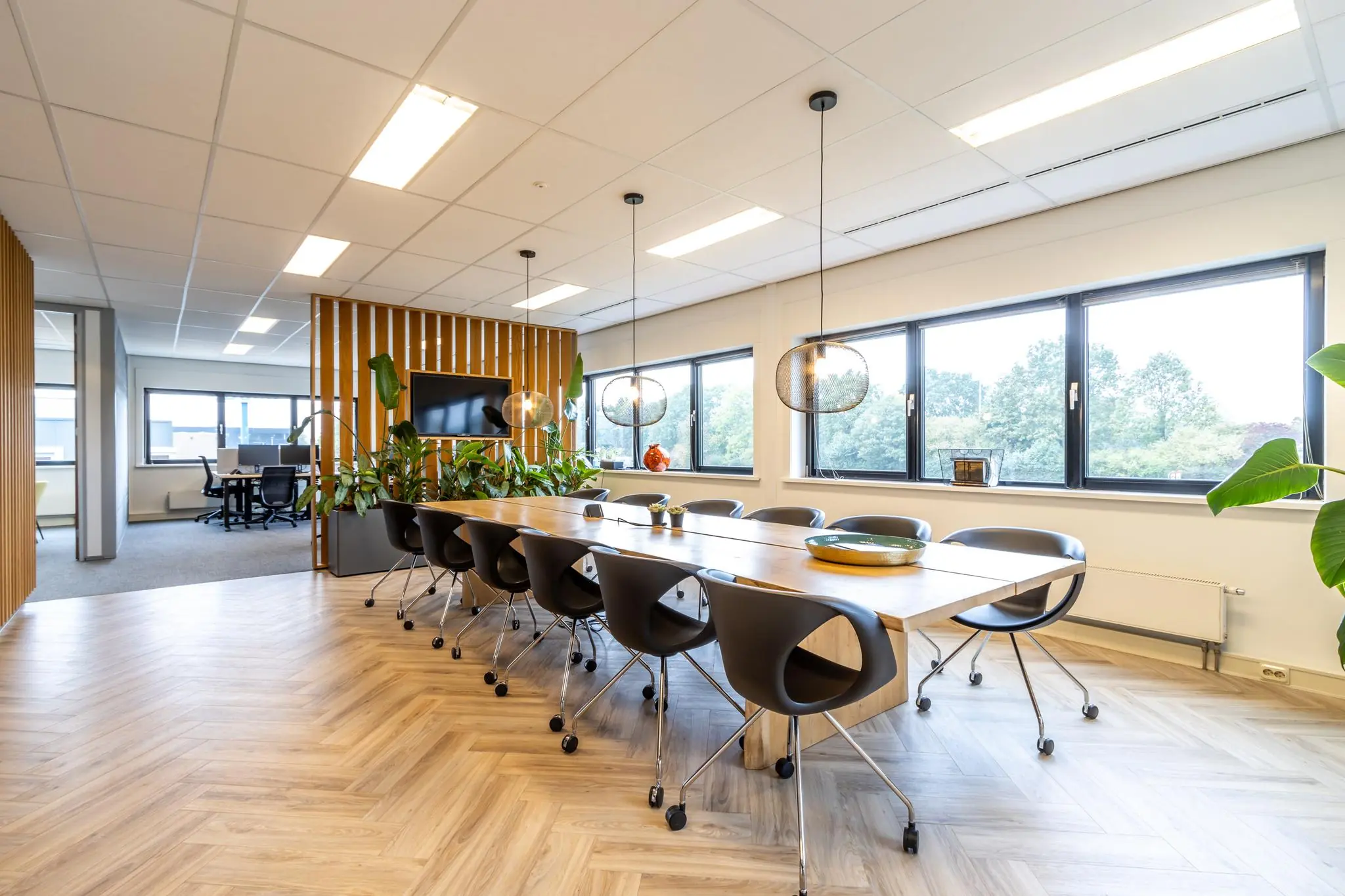 Moderne vergaderruimte aan de Lage Biezenweg met houten vloer, grote tafel, designstoelen en veel daglicht.